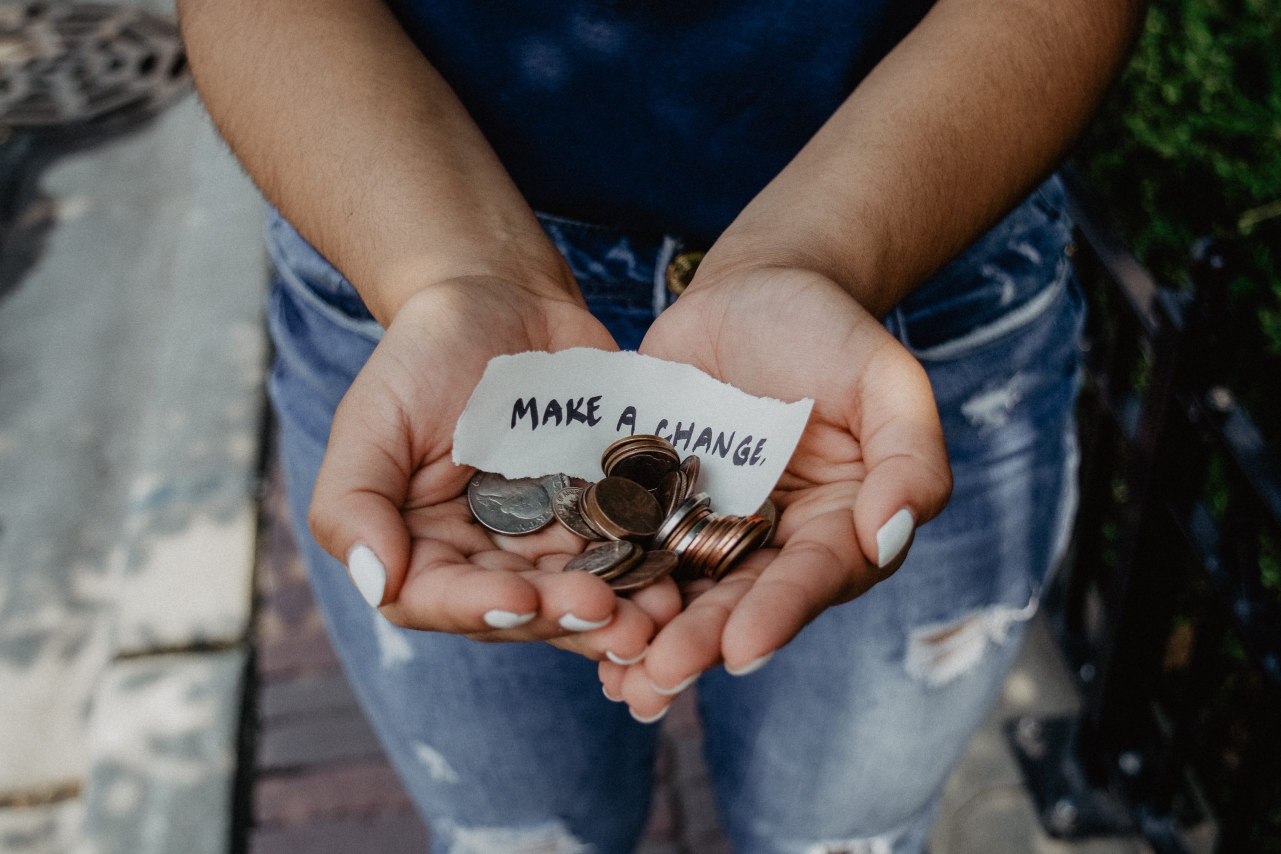 woman holding "make a change" note and coins in hands